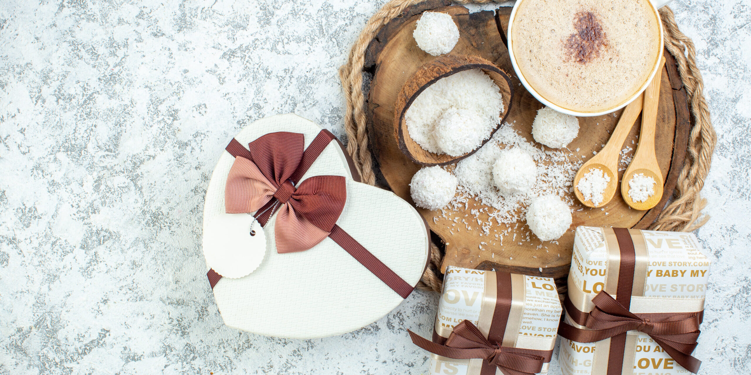 top-view-cappuccino-cup-coconut-powder-bowl-wooden-spoons-wood-board-gifts-heart-shaped-giftbox-grey-surface